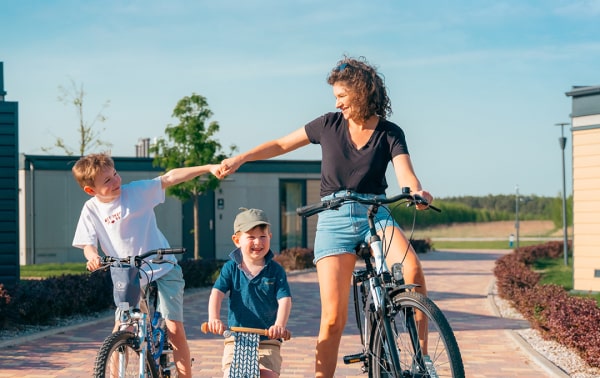 Kobieta i dwoje dzieci cieszą się przejażdżką rowerową po urokliwej brukowanej ścieżce.